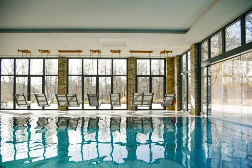 an indoor swimming pool with chairs and windows at Landhotel Burg im Spreewald - Resort & Spa in Burg