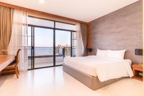 a bedroom with a large bed and a balcony at Sea Sand Sun Hua Hin by JC Kevin Hotel & Resort in Phetchaburi