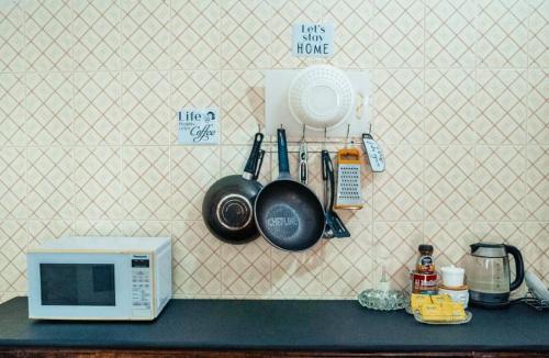 a counter with a microwave and utensils on a wall at Digital nomad Cave- Zanzibar in Stone Town