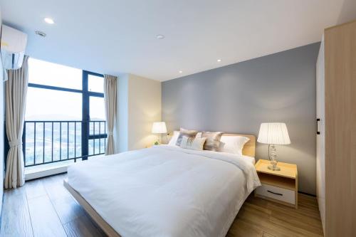 a white bedroom with a large bed and a window at Serveyou International Apartment - Free Airport Pickup Service & Free Pazhou Complex Shuttle Bus & Free Sanyuan Li Xiaobei Baiyun Wholesale Market shuttle bus in Guangzhou