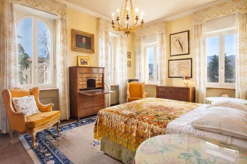 een slaapkamer met een bed, een stoel en ramen bij Villa Lidia-Dimora storica a Caprino Veronese in Caprino Veronese