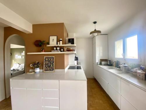 a kitchen with white cabinets and a white counter top at Appartement familial, vue canal Ourcq, parking in Pantin