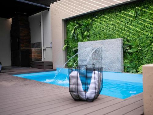 a pool with a water fountain in front of a wall at The Lofts Prestige Suites in Windhoek