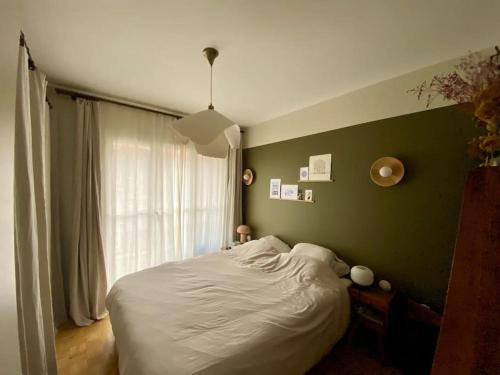a bedroom with a white bed and a green wall at Appartement familial, vue canal Ourcq, parking in Pantin