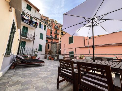 a patio with benches and an umbrella on a building at Luxury Apartments Manarola by Arbaspàa in Manarola