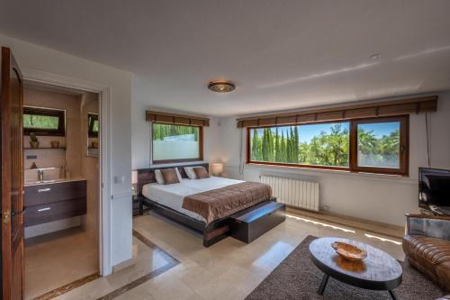 ein Schlafzimmer mit einem Bett, einem Waschbecken und einem Sofa in der Unterkunft Luxury country house with pool and breathtaking views in Casares