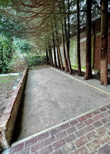 a brick walkway with trees in front of a building at Le Manoir de la belle epoque in Béthencourt-sur-Mer