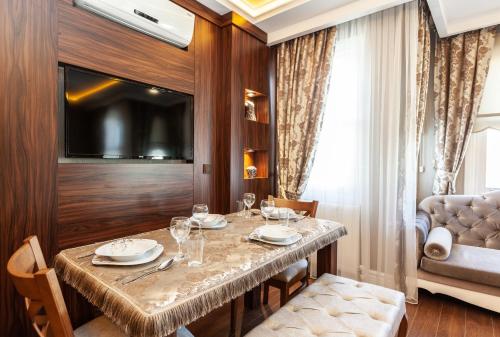 uma sala de jantar com uma mesa e uma televisão em Rose Apartments em Istambul