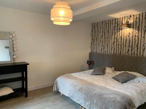 une chambre avec un grand lit et un lustre dans l'établissement L’appart Quessoy, à Quessoy