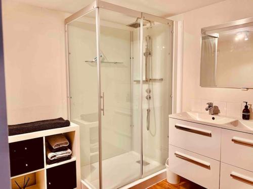 ein weißes Bad mit einer Dusche und einem Waschbecken in der Unterkunft L’appart Quessoy in Quessoy