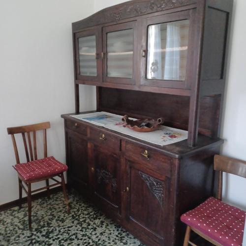 a wooden cabinet with a window and two chairs at Alloggio Grande Joséphine in Oulx