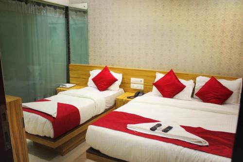 2 letti in camera con cuscini rossi e bianchi di MAROL METRO HOTEL MUMBAI a Mumbai