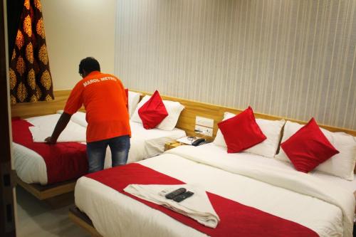 a man standing between two beds in a hotel room at MAROL METRO HOTEL MUMBAI in Mumbai