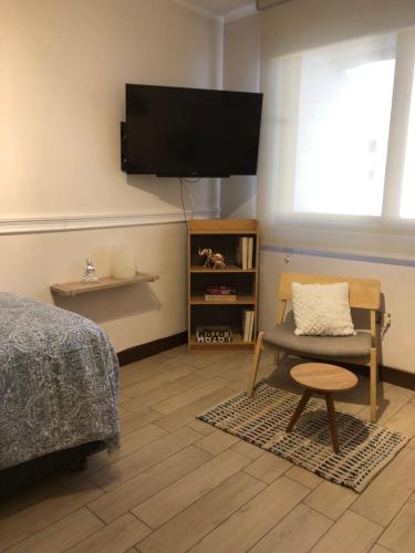 - une chambre avec un lit, une chaise et une télévision à écran plat dans l'établissement Departamento Fray León, à Santiago