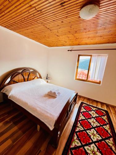 a bedroom with a large bed with a wooden ceiling at Nena’s Dashe House in Berat