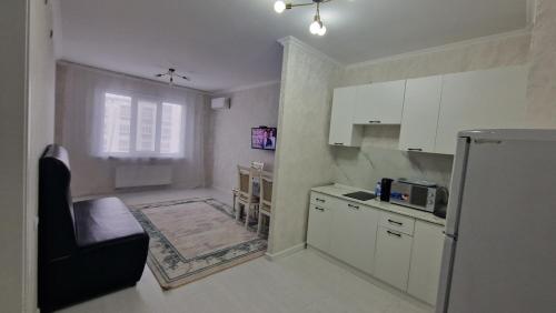 a kitchen with white cabinets and a black chair at Jetysu2 in Prigorodnyy