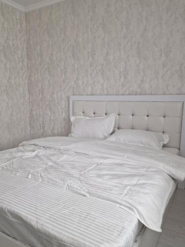 a white bed with white sheets and pillows at Jetysu2 in Prigorodnyy