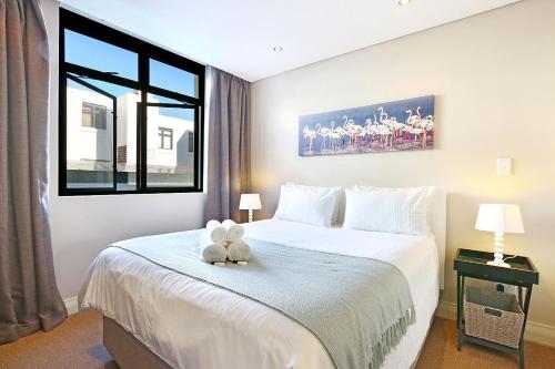 a bedroom with a bed with two teddy bears on it at Eden On The Bay 118 by HostAgents in Bloubergstrand