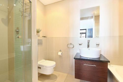 a bathroom with a toilet and a sink and a shower at Eden On The Bay 118 by HostAgents in Bloubergstrand