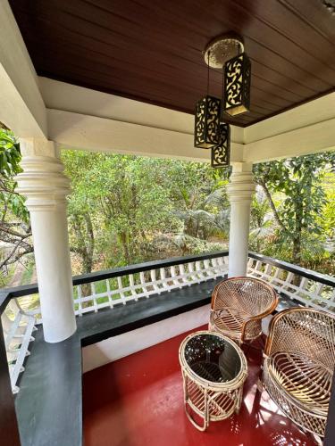 a porch with chairs and a table and a window at Thoppil Homestay Munnar in Munnar