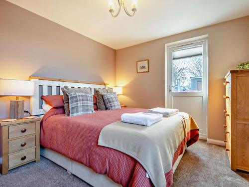 um quarto com uma cama com um cobertor vermelho e uma janela em 1 Bed in Crackington Haven 93958 em Jacobstow