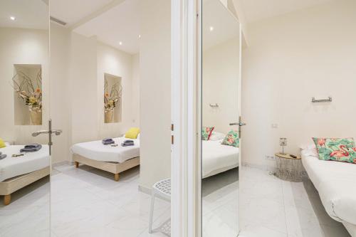 um quarto branco com 2 camas e um espelho em CMG Cannes / Plage Barrière em Cannes