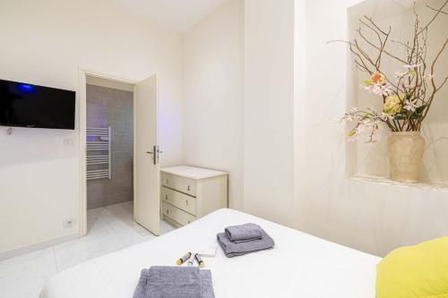 um quarto branco com uma cama e uma televisão em CMG Cannes / Plage Barrière em Cannes