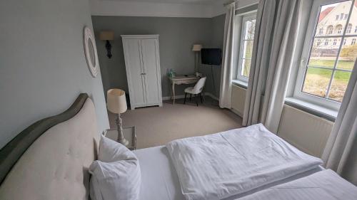 a bedroom with a bed and a desk and a window at Schloss Krugsdorf Golf & Hotel in Krugsdorf