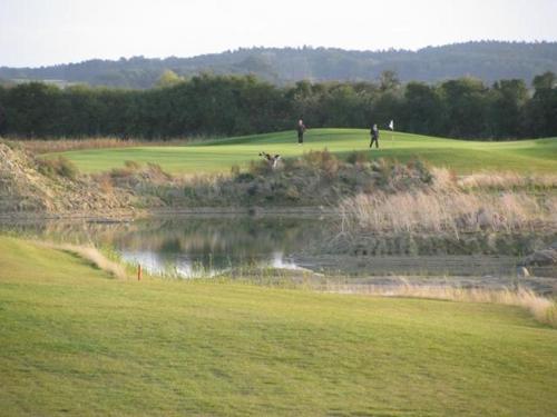 two people playing golf on a golf course with a pond at Schloss Krugsdorf Golf & Hotel in Krugsdorf