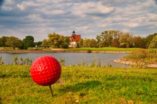 a red golf ball sitting in the grass next to a lake at Schloss Krugsdorf Golf & Hotel in Krugsdorf