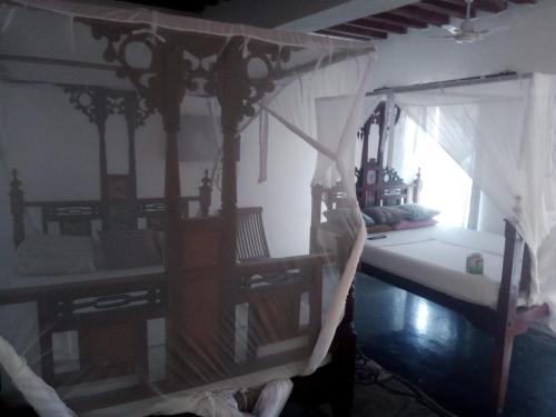 ein Schlafzimmer mit einem Himmelbett und einem Fenster in der Unterkunft Bahari Hotel in Lamu