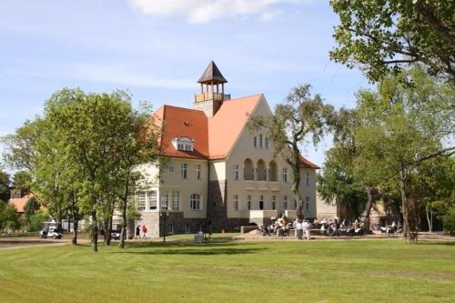 a large white building with a tower on top of it at Schloss Krugsdorf Golf & Hotel in Krugsdorf