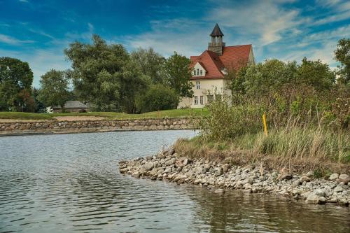 a house on the side of a river with a building at Schloss Krugsdorf Golf & Hotel in Krugsdorf