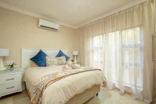 um quarto com uma cama com almofadas azuis e uma janela em EDJAMI Guest House em Marloth Park