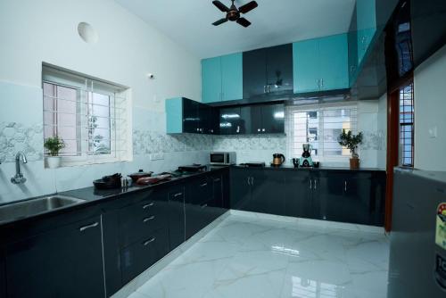 a kitchen with black cabinets and a ceiling fan at Yellow Bells Serviced Apartments Hitech City in Hyderabad