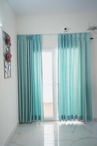 a room with blue curtains and a large window at Yellow Bells Serviced Apartments Hitech City in Kondapur