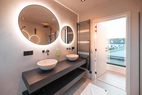 twee wastafels in een badkamer met twee spiegels bij Villa Midi in De Haan
