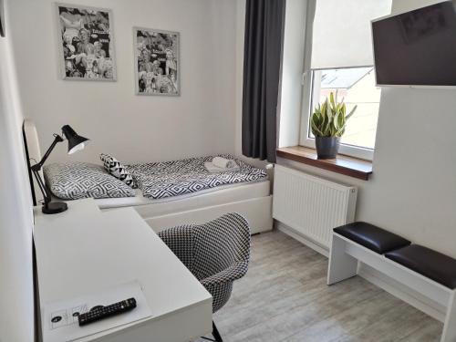 a small room with a bed with a desk and a window at Hotel Na Baste in Jablonec nad Nisou