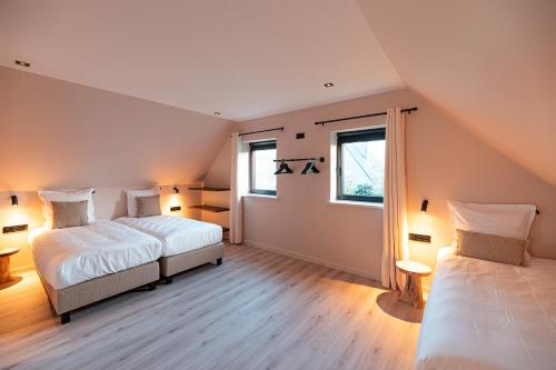 twee bedden in een kamer met twee ramen bij Villa Midi in De Haan