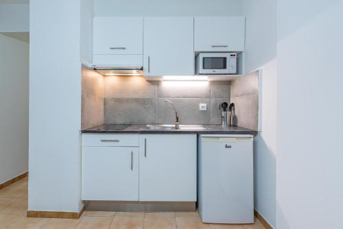 a kitchen with white cabinets and a sink at Aptos. Comte D´Empuries in Empuriabrava