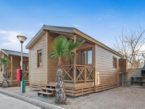 a small cabin with a palm tree in front of it at Devesa Gardens in El Saler