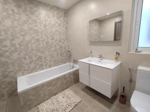 un bagno con vasca, lavandino e vasca tubermott di San Pawl Lodge Hostel a San Pawl il-Baħar
