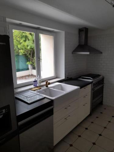 a kitchen with a sink and a window at Belle maison du 18e siècle in Bazemont