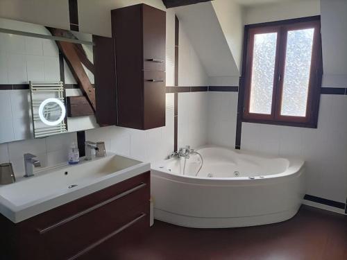a bathroom with a large tub and a sink at Belle maison du 18e siècle in Bazemont