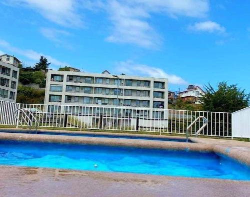 a swimming pool with a building in the background at Depto. con vista al mar 4° piso, Tomé, Dichato in Tomé