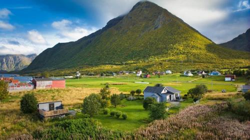 a small town in a field with a mountain at Koselig bolig i Lofoten / Vesterålen in Strønstad