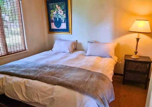 a bedroom with a large bed with white sheets and pillows at Imbabali Retreat & Venue in Magaliesburg
