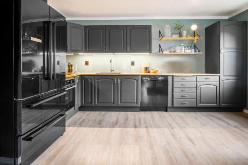 a kitchen with black cabinets and a wooden floor at Koselig bolig i Lofoten / Vesterålen in Strønstad