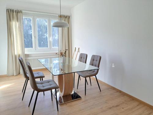 comedor con mesa de cristal y sillas en Airolo Valley Apartments by Quokka 360 - Cozy with Mountain View, en Airolo