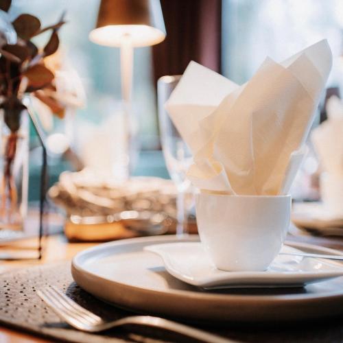 a table with a plate with a cup of napkin at Hotel-Restaurant Peifer in Brodenbach